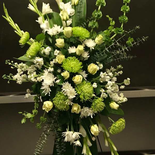 Tall green and white standing spray with roses, mums, and bells of Ireland on a metal easel