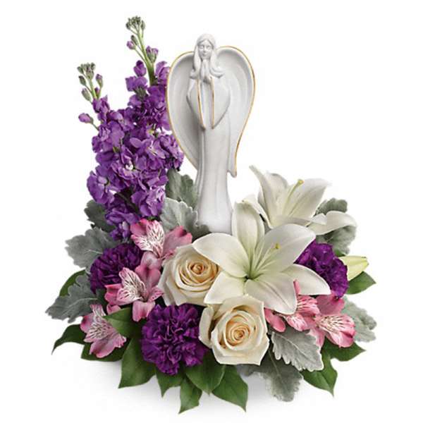 Sympathy arrangement with white angel figurine, white lilies, purple blooms, and cream roses.