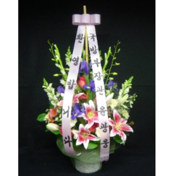 Tall floral arrangement with pink lilies and purple flowers in a pot, accented by long Korean message ribbons.