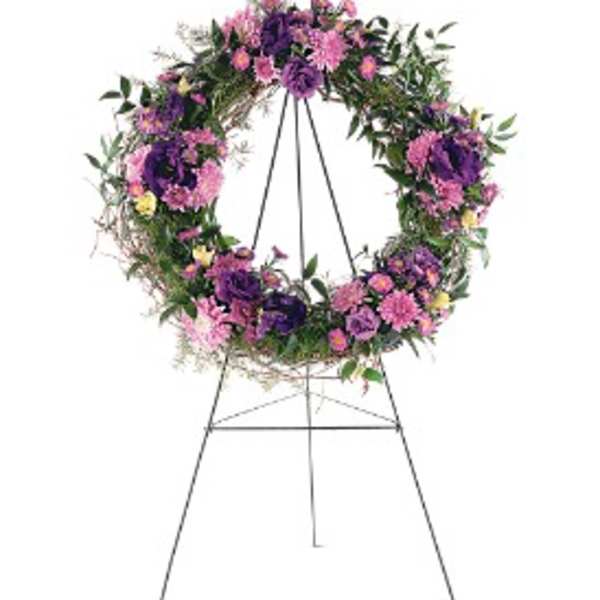 Standing wreath of purple and pink flowers on a black metal easel