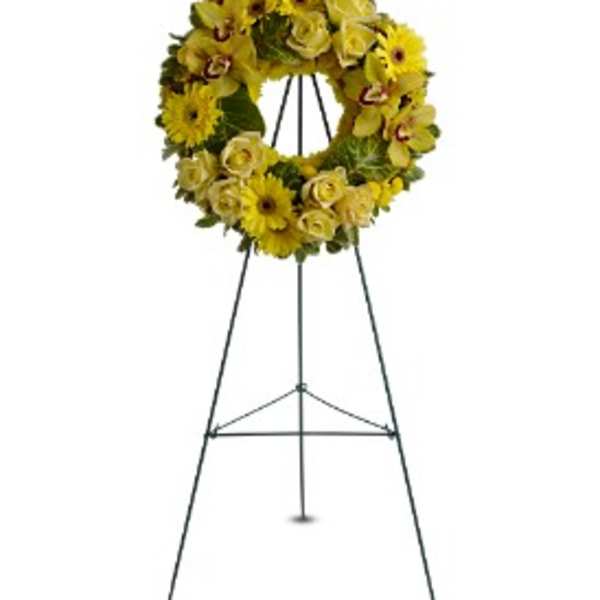 Yellow floral wreath displayed on a tall metal easel stand