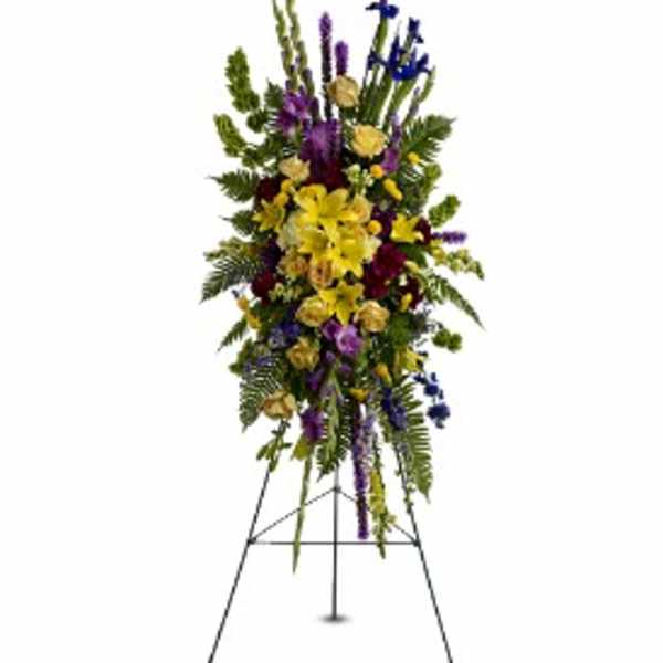 Tall standing spray of yellow lilies and mixed purple and blue flowers on a metal easel