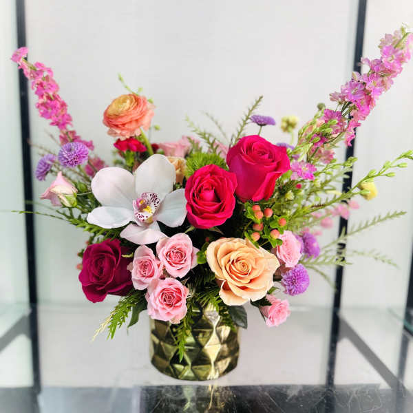 Mixed bouquet of roses and orchids in a gold vase