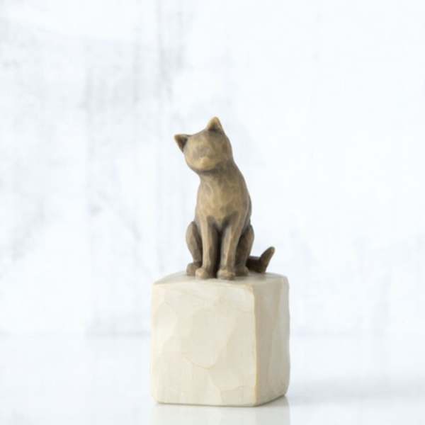 Small cat figurine sitting on a square pedestal