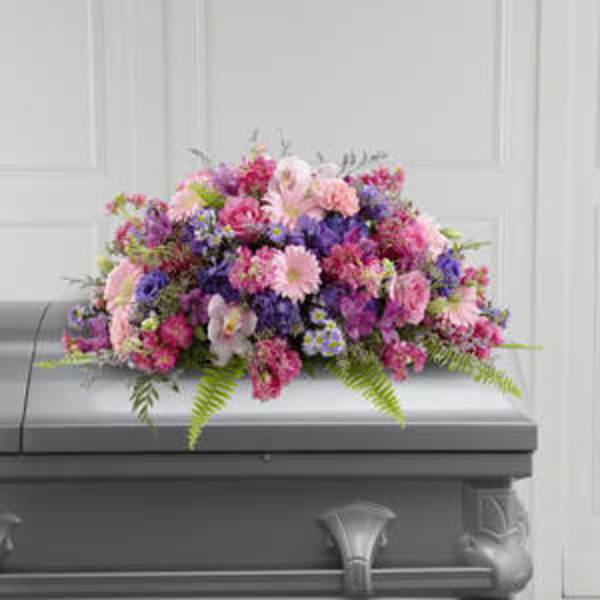 Pink and purple floral casket spray on a gray coffin