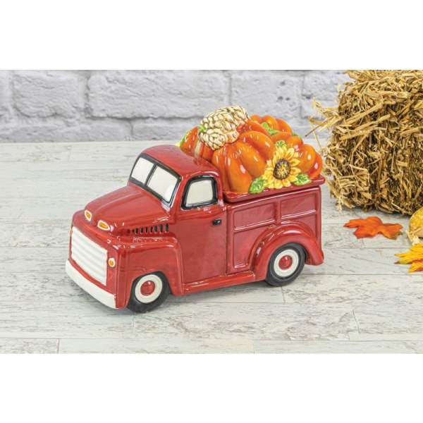 Red ceramic truck figurine filled with pumpkins and a sunflower