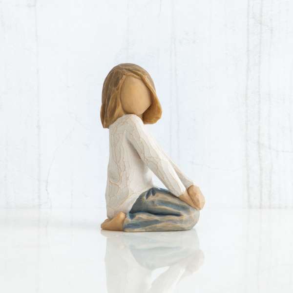 Small seated figurine of a girl in a white top and blue pants