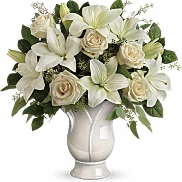White lilies and cream roses arranged in a white vase