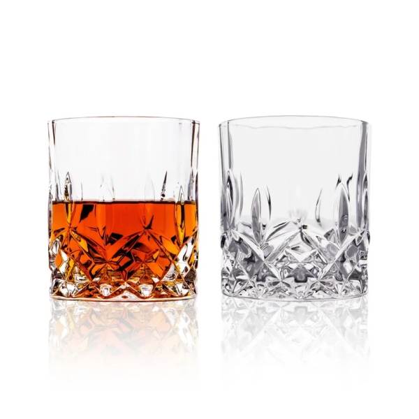 Two faceted drinking glasses, one filled with amber liquid
