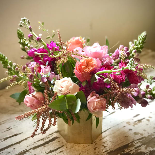 Pink and coral roses arranged in a gold vase