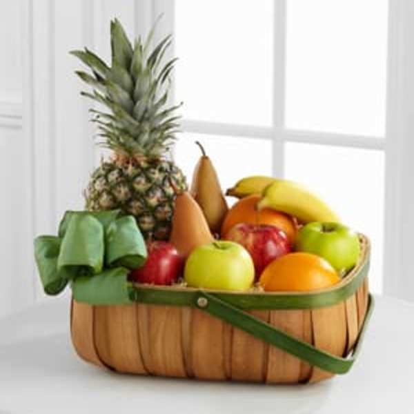 Fruit basket with pineapple, bananas, apples, and pears in a woven basket