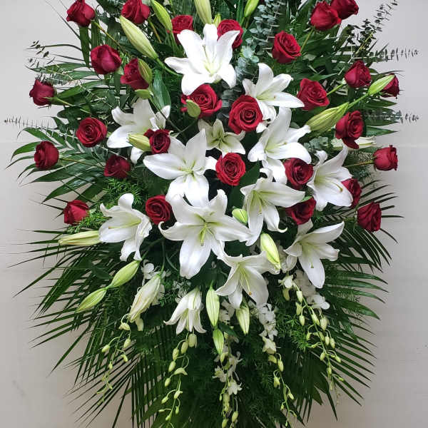 Tall standing spray of red roses and white lilies displayed on an easel