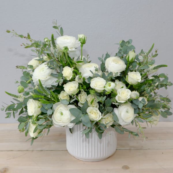 White rose and ranunculus arrangement in a ribbed white vase
