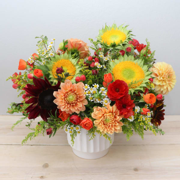 Mixed bouquet with sunflowers, dahlias, and roses in a white vase