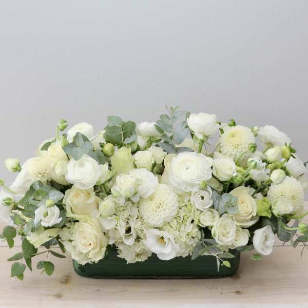 White floral arrangement in a low green container