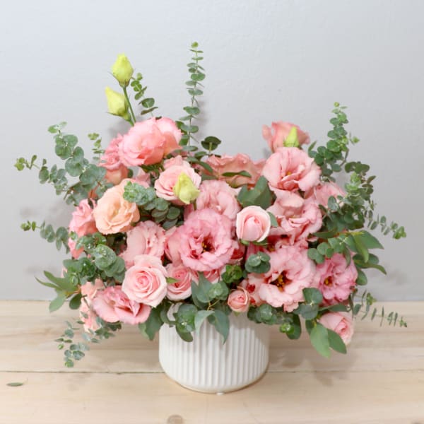 Pink roses and lisianthus in a white ribbed vase