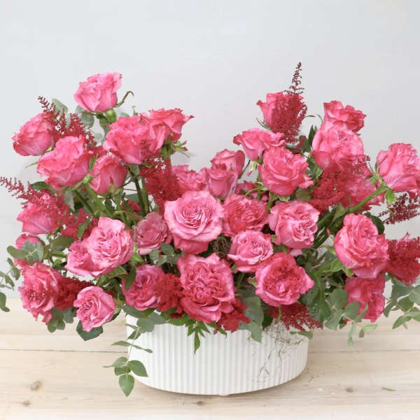Pink rose arrangement in a white ribbed vase
