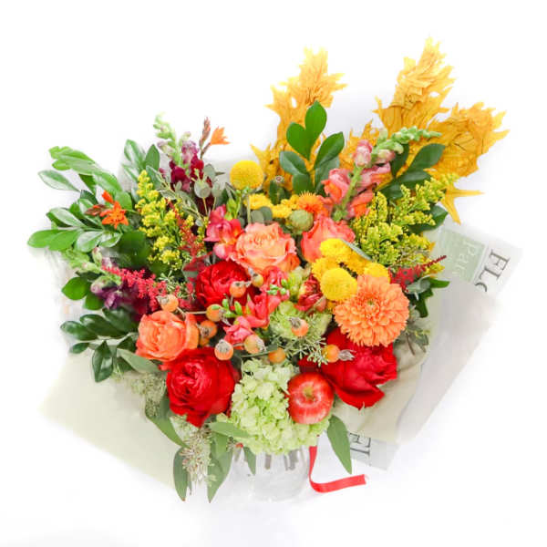 Mixed bouquet of red, orange, and yellow flowers in a clear vase