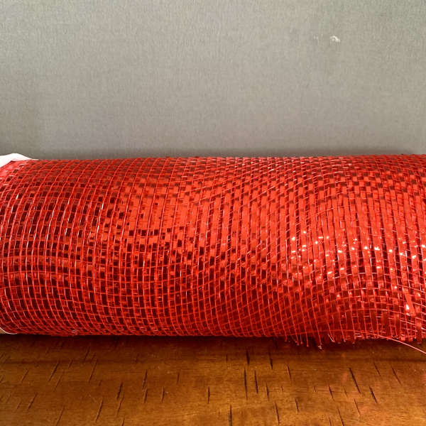 Roll of red mesh ribbon on a wooden surface