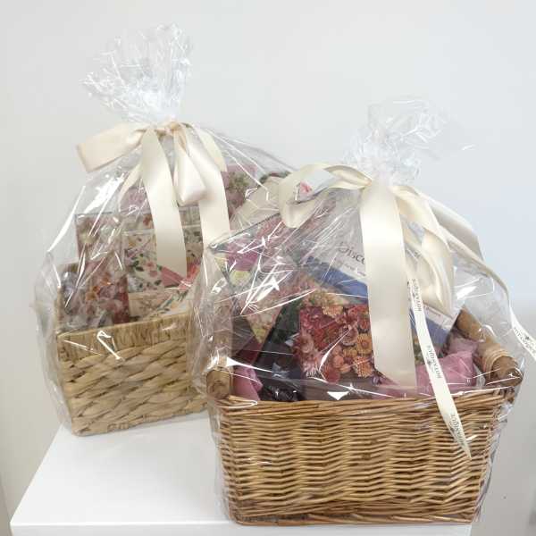 Two wrapped gift baskets with ribbon bows on a white surface