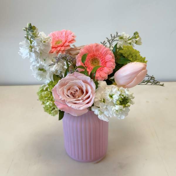 Pink and white flower arrangement in a ribbed pink vase