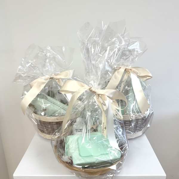 Three wrapped gift baskets with cream ribbons on a white surface