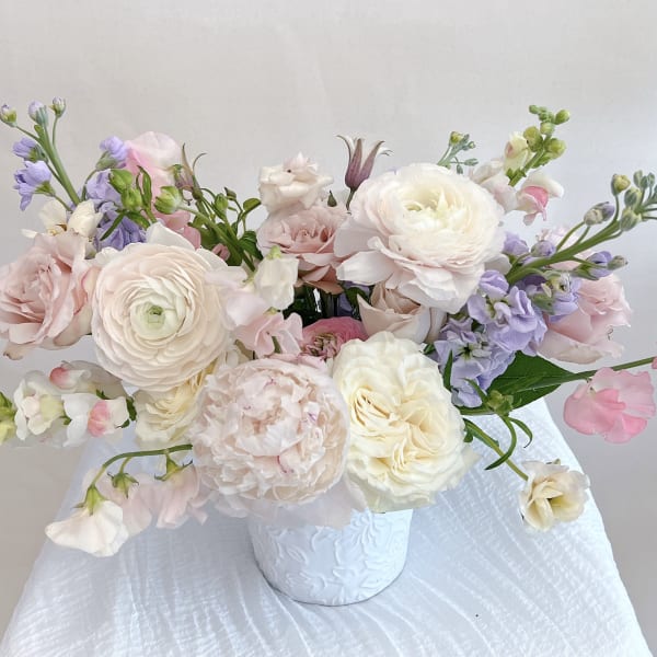 Pastel bouquet of roses and ranunculus in a white vase