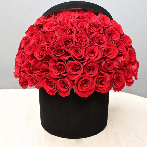 Dome of red roses arranged in a round black hatbox-style container