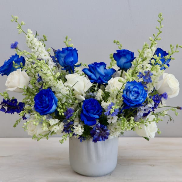 Blue and white flower arrangement in a white ceramic vase