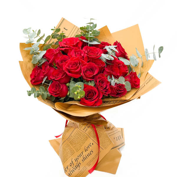 Bouquet of red roses wrapped in tan paper with eucalyptus