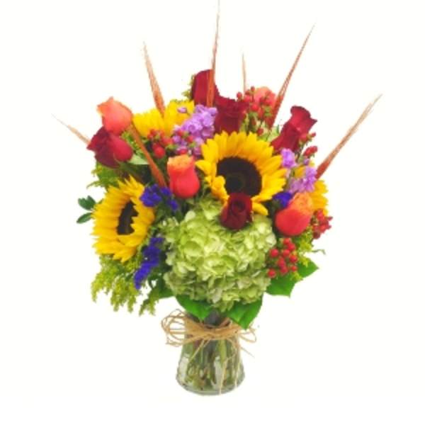 Bouquet of sunflowers, roses, hydrangea, and mixed blooms in a glass vase