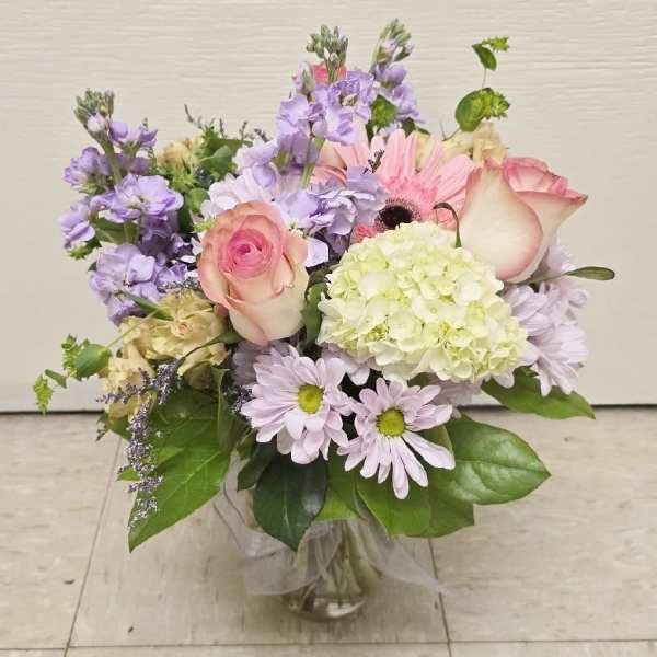 Pastel bouquet in a glass vase with roses, hydrangea, and daisies