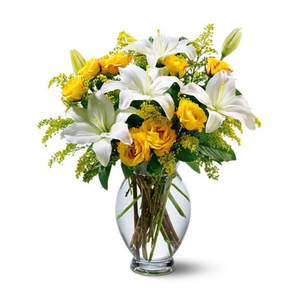 White lilies and yellow roses arranged in a clear glass vase