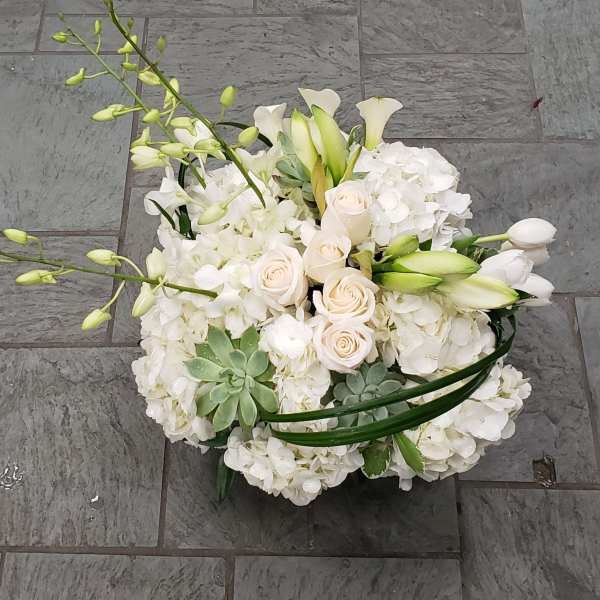 White floral arrangement with roses, orchids, and calla lilies