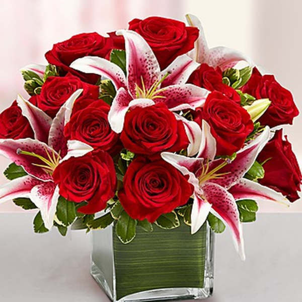 Red roses and pink lilies in a square glass vase