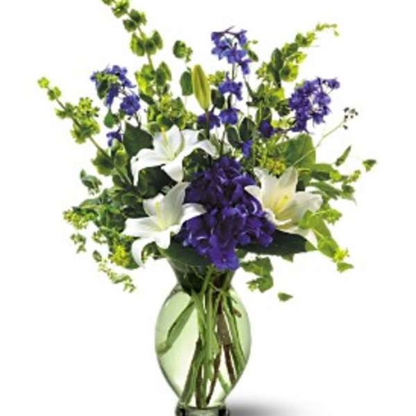 White lilies and purple flowers in a glass vase