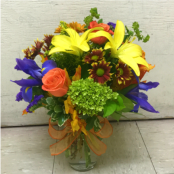 Colorful mixed bouquet in a clear glass vase with a ribbon bow