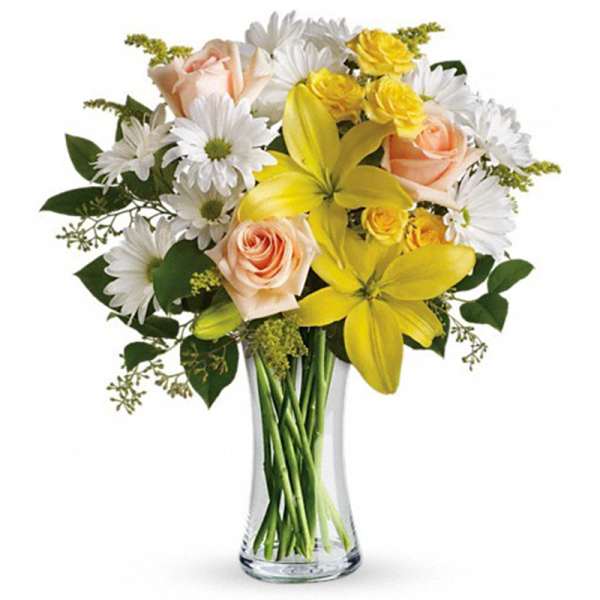 Bouquet of yellow lilies, white daisies, and peach roses in a clear glass vase