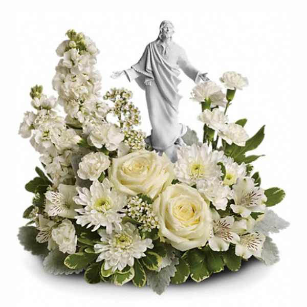 White floral arrangement with roses and a central white religious figurine