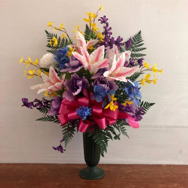 Tall mixed silk flower arrangement with pink lilies, purple and blue blooms, and yellow accents in a green vase