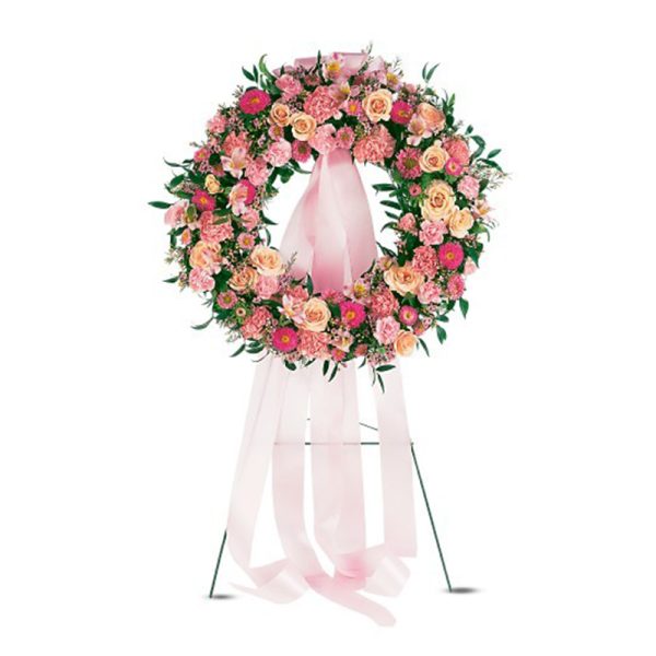 Pink and peach floral standing wreath with long pink ribbons on a metal easel