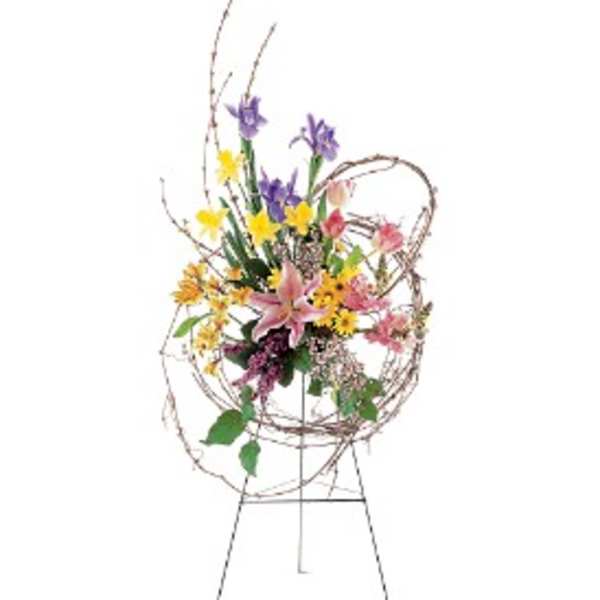 Tall standing easel with a circular twig frame filled with bright mixed spring flowers