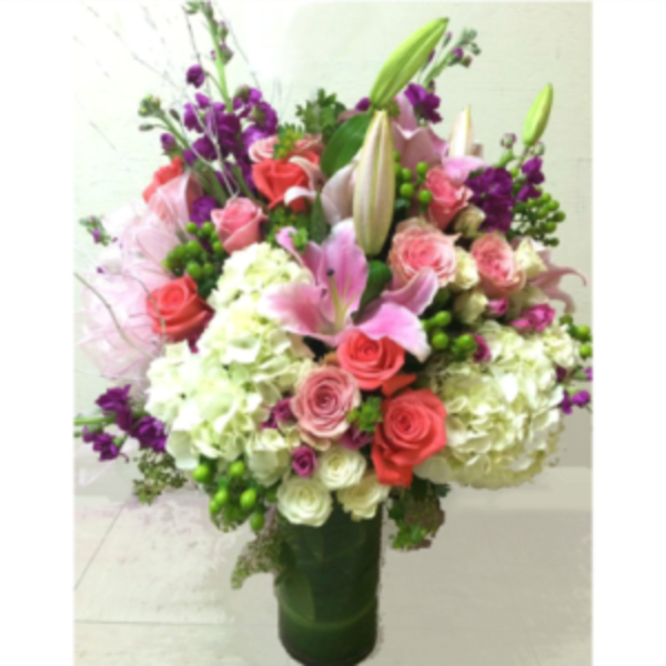 Mixed bouquet of pink, white, and purple flowers in a tall vase