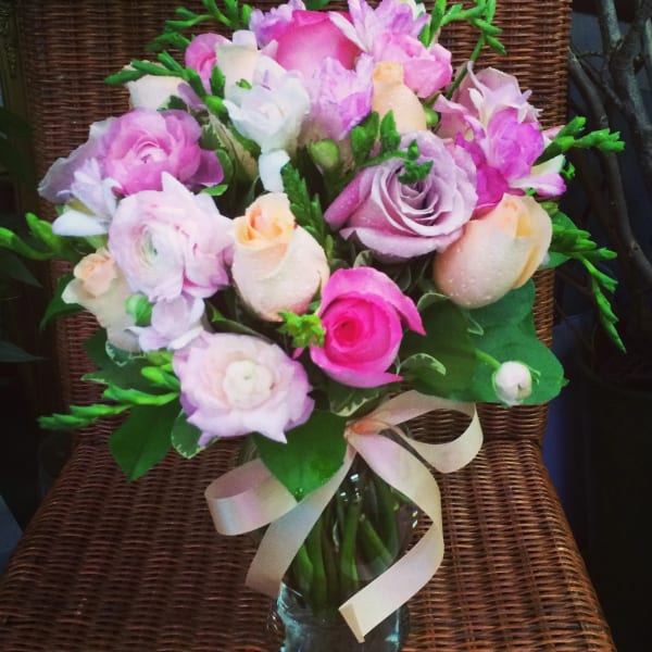 Pink and lavender bouquet in a glass vase with a ribbon