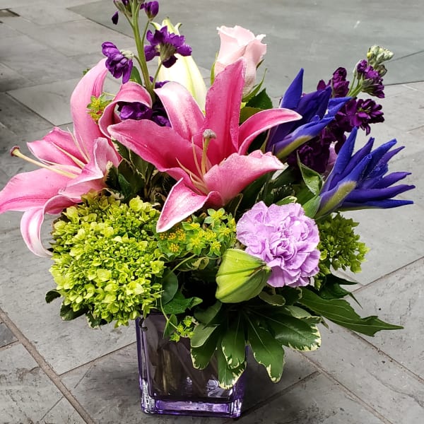 Pink and purple lilies arranged in a purple glass vase