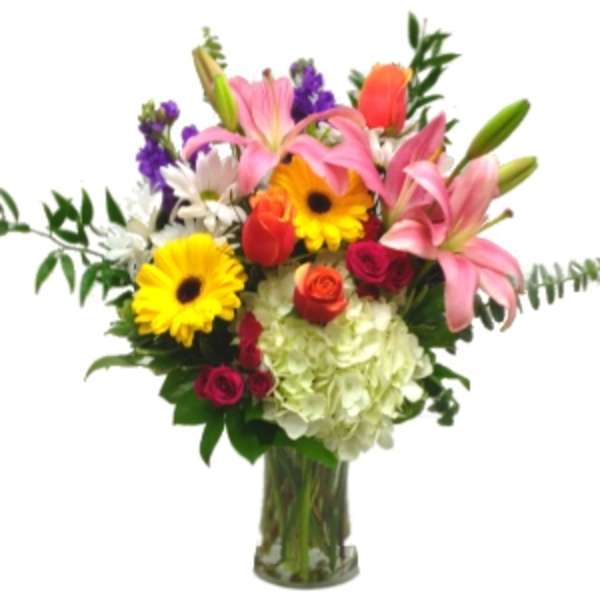 Mixed bouquet with lilies, gerbera daisies, roses, and hydrangea in a glass vase