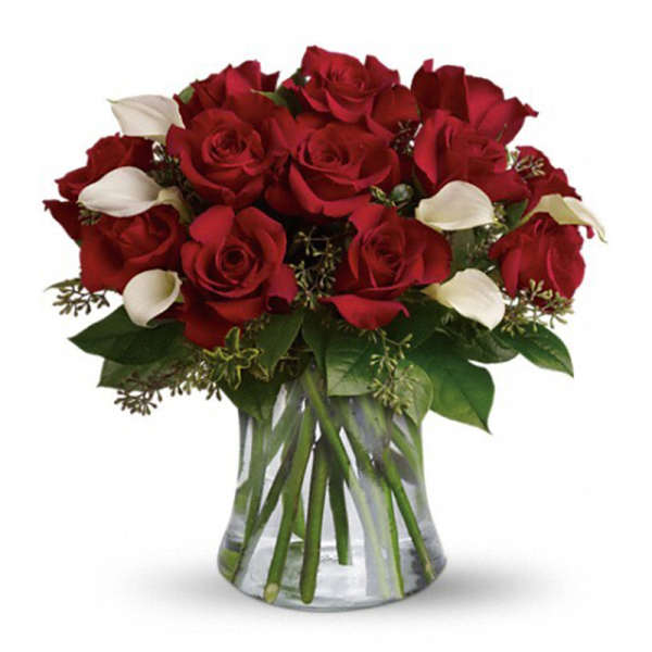 Red roses and white calla lilies in a clear glass vase