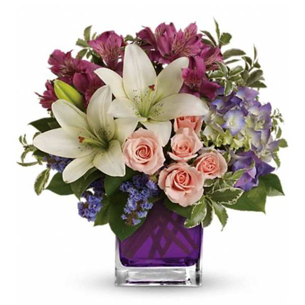Bouquet of white lilies, pink roses, and purple flowers in a purple vase