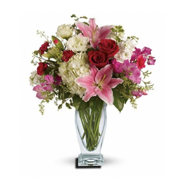 Bouquet of pink lilies, red roses, and white blooms in a glass vase
