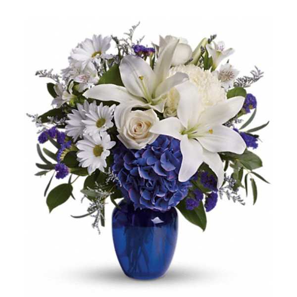 White lilies and daisies with blue hydrangea in a cobalt vase